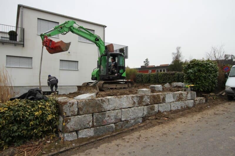 Bagger der Egli Gartenbau AG Uster bei der Erstellung einer Stützmauer und eines Schwimmbads.