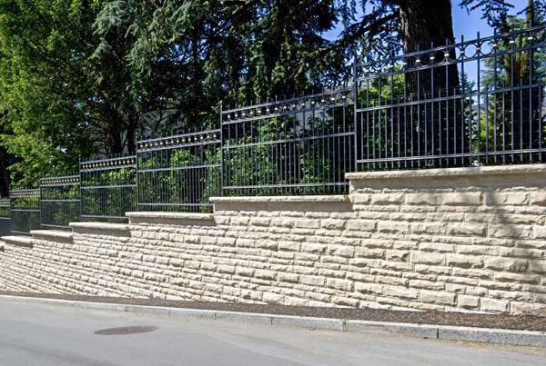 Natursteinmauer mit schmiedeisernem Zaun