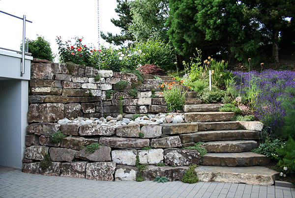 Die plattige Natursteintreppe ist aus dem gleichen Material wie die Mauern