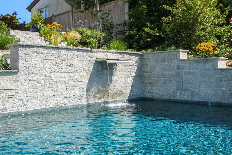 Die Schwalldusche ist in die Natursteinmauer am Pool integriert