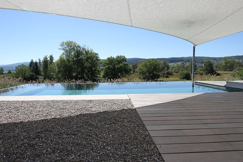 Kiesfläche und Holzrost mit Sonnensegel am Swimmingpool