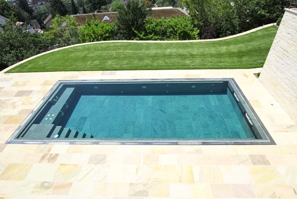 Swimmingpool mit schöner Natursteinaukleidung und gelbem Natursteinplattenbelag.