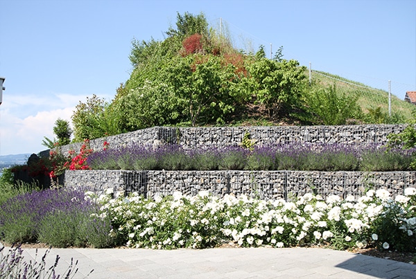 Schotterkörbe als Mauer, welche wunderschön bepflanzt wurde und als Hangsicherung dient.